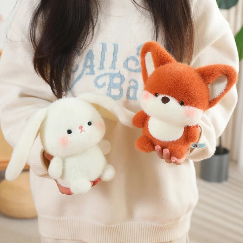 Person holding a white rabbit plush kawaii toy and an orange fox plush toy.