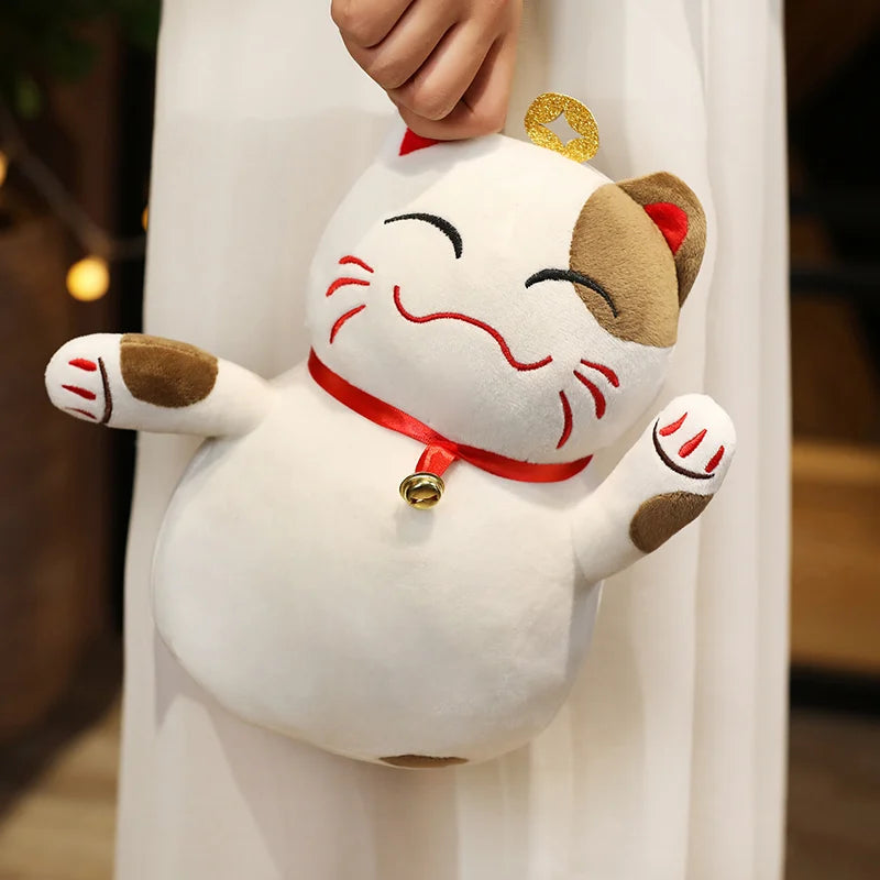Kawaii plush toy shaped like a cat with a bell, held by a person wearing a white outfit.