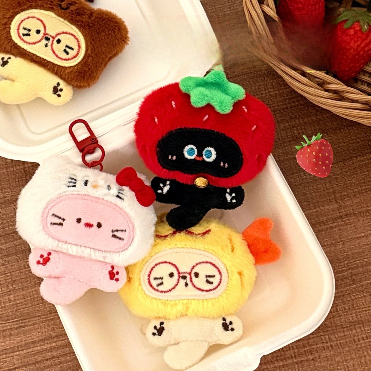 Set of kawaii plush keychains on a white tray with strawberries in the background