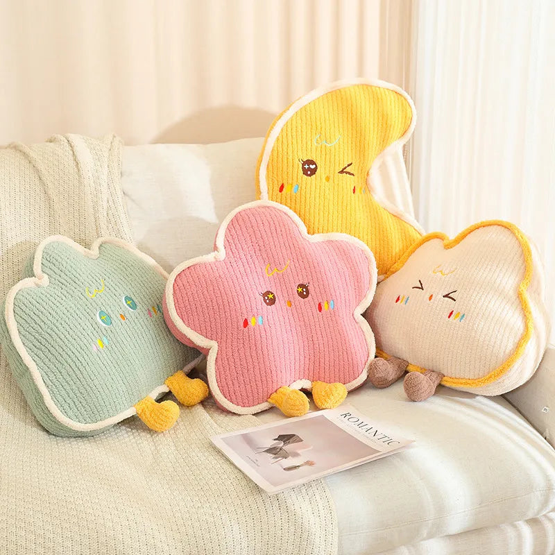 Four colorful cloud-shaped kawaii cushions with cartoon faces on a couch.