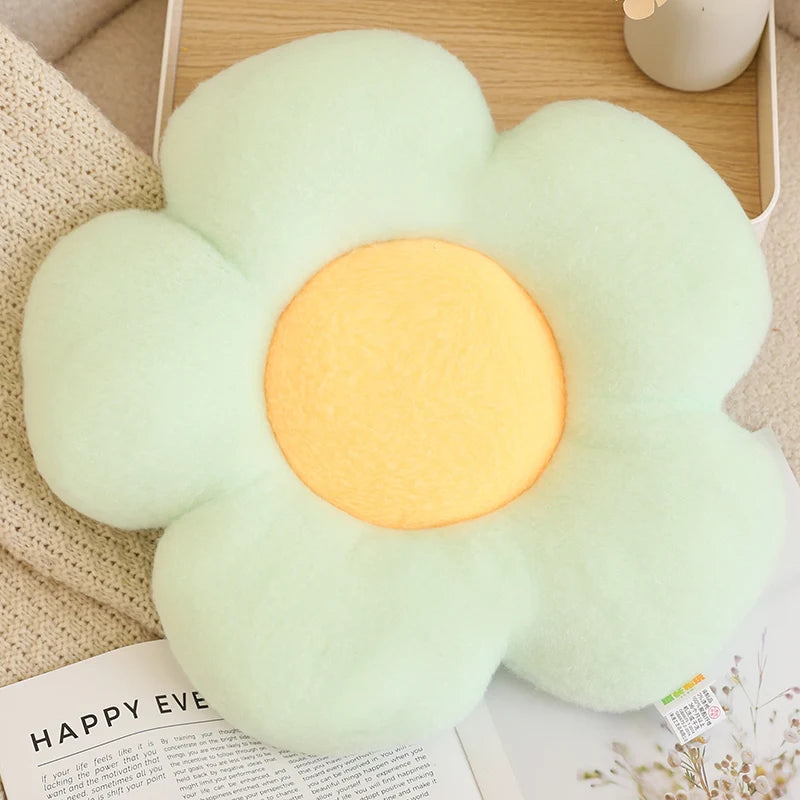 Flower-shaped kawaii cushion with a glowing center on a surface with a magazine underneath.