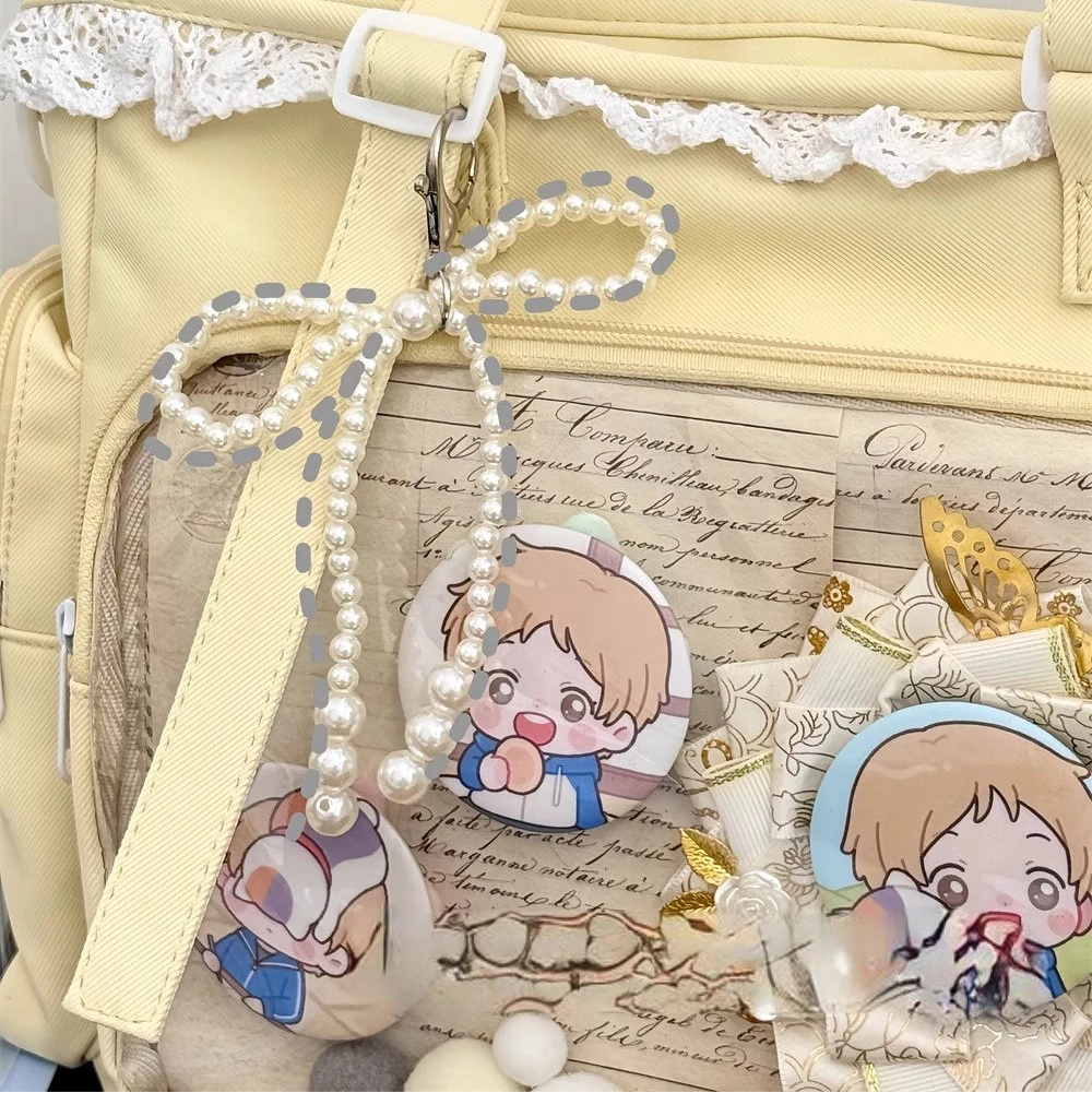 Light yellow bag with Kawaii cartoon character stickers and a pearl strap on a textured surface.