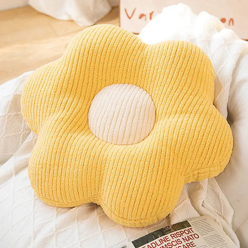 Yellow flower-shaped kawaii pillow on a bed with a blurred background