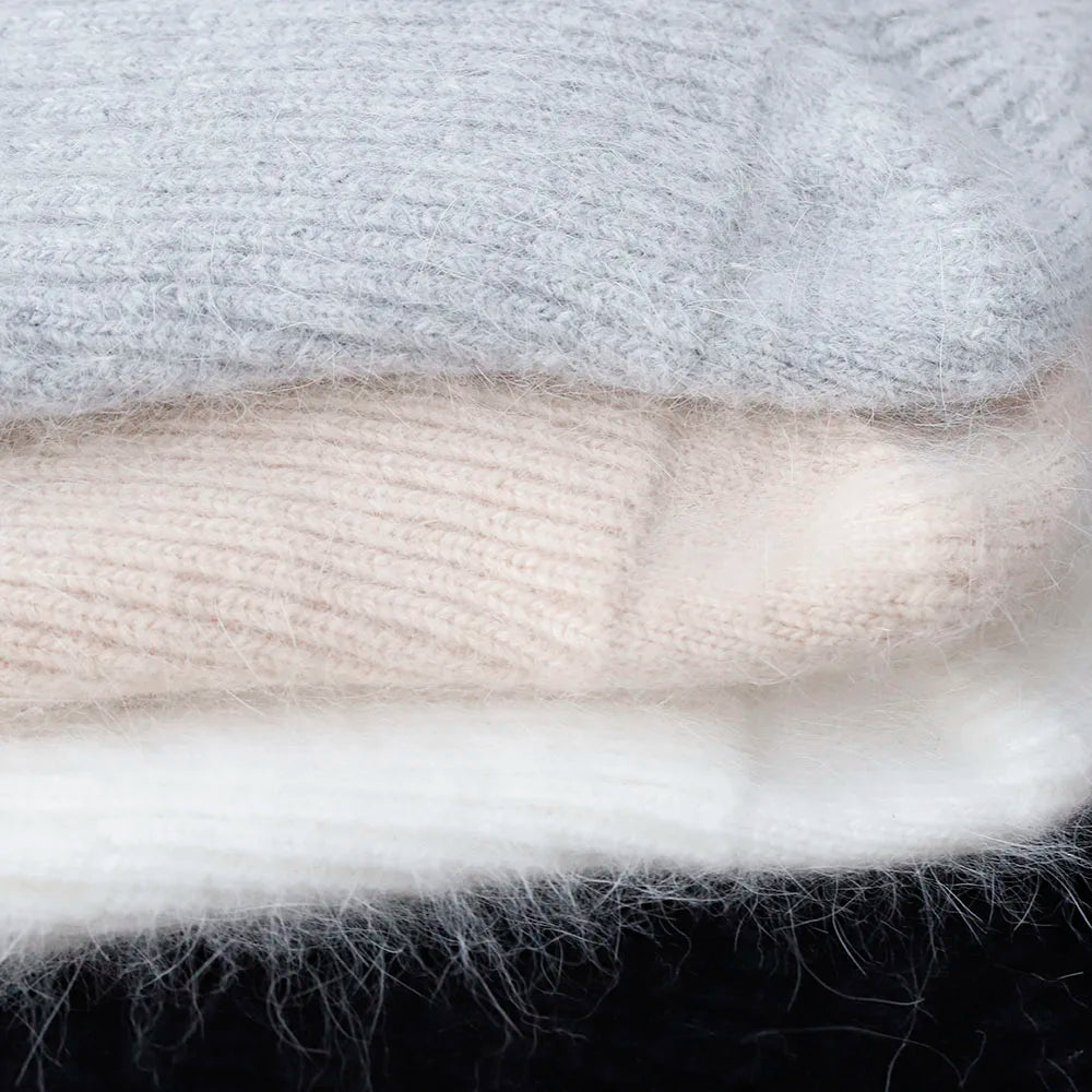Close-up of gray, white, and black Kawaii hats stacked on a dark background