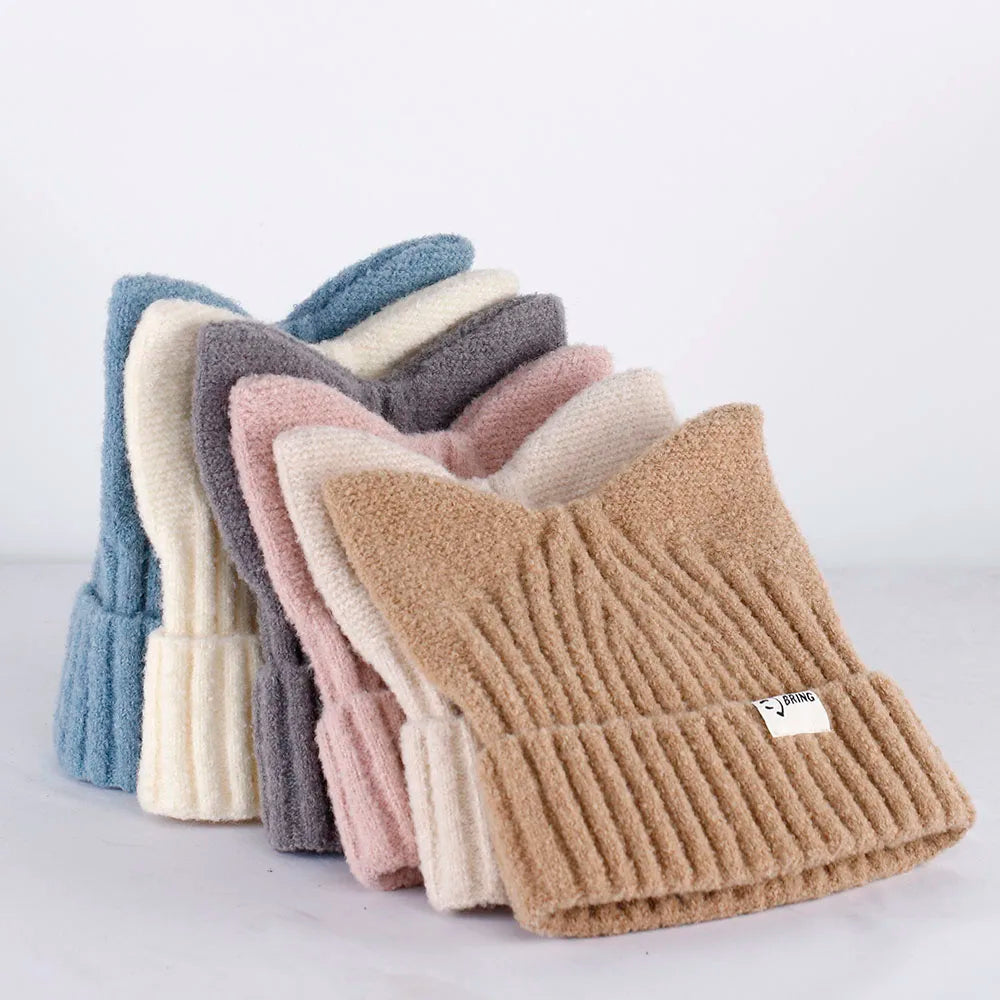 Stack of knitted Kawaii hats in various colors on a light background