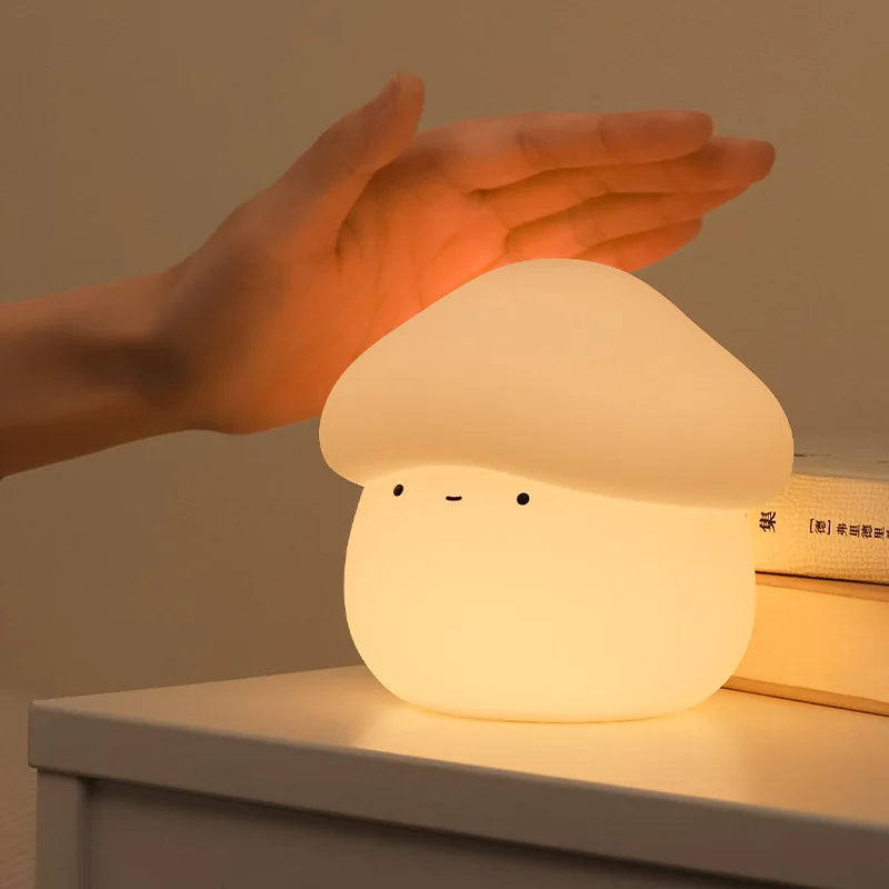 Mushroom-shaped kawaii night light being held by a hand on a surface with a warm glow.