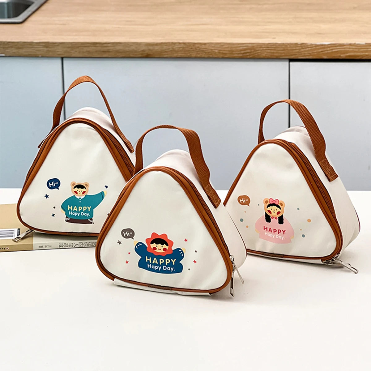 Three triangular bags with kawaii cartoon characters and 'Happy Day' text on a kitchen counter.