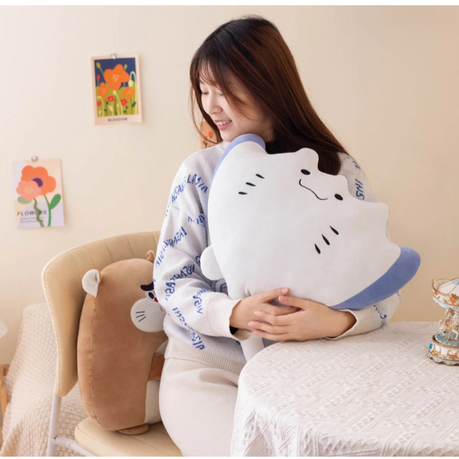 Person holding a large cat-shaped kawaii pillow in a cozy room.
