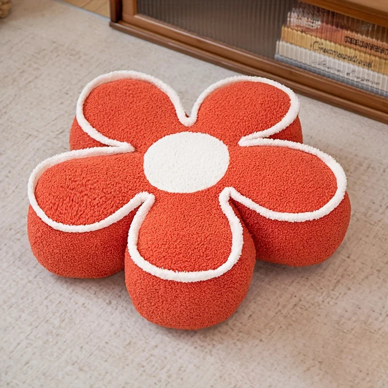 Flower-shaped kawaii cushion with orange petals and white center on a beige carpet