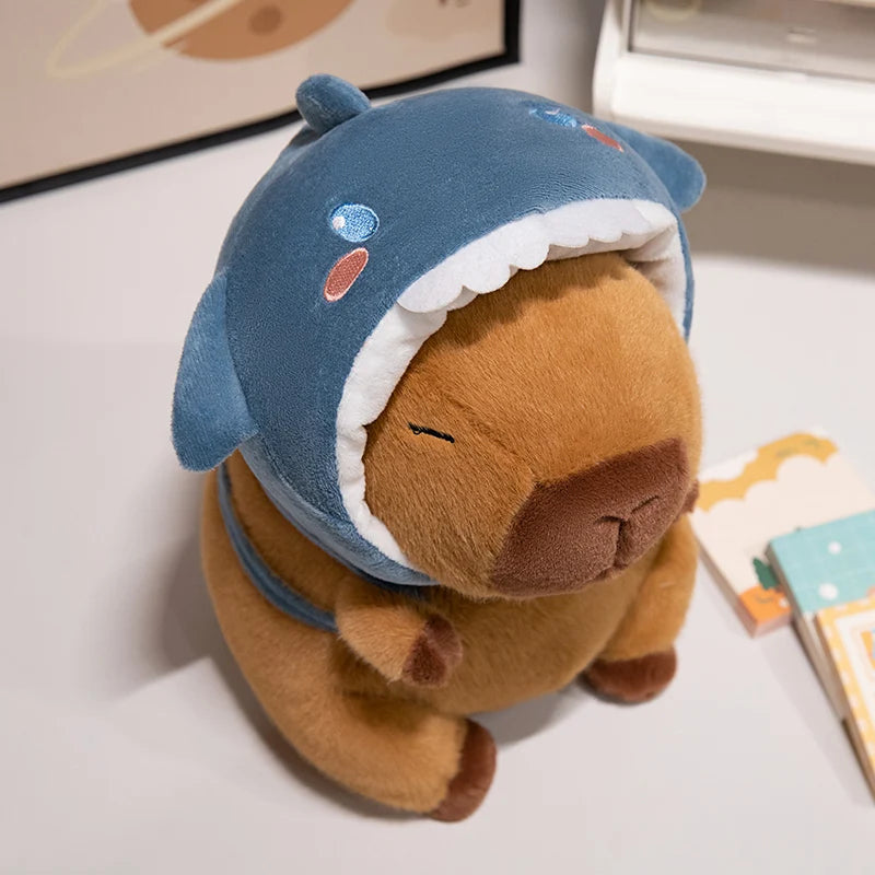 Kawaii plush toy bear wearing a blue shark costume on a light surface.