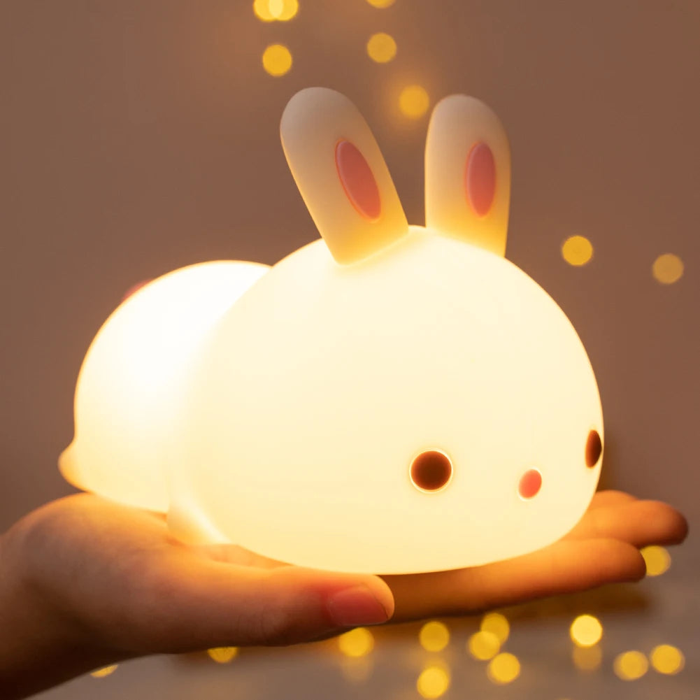 Cute rabbit-shaped kawaii night light held in a hand with a warm glow against a blurred background.