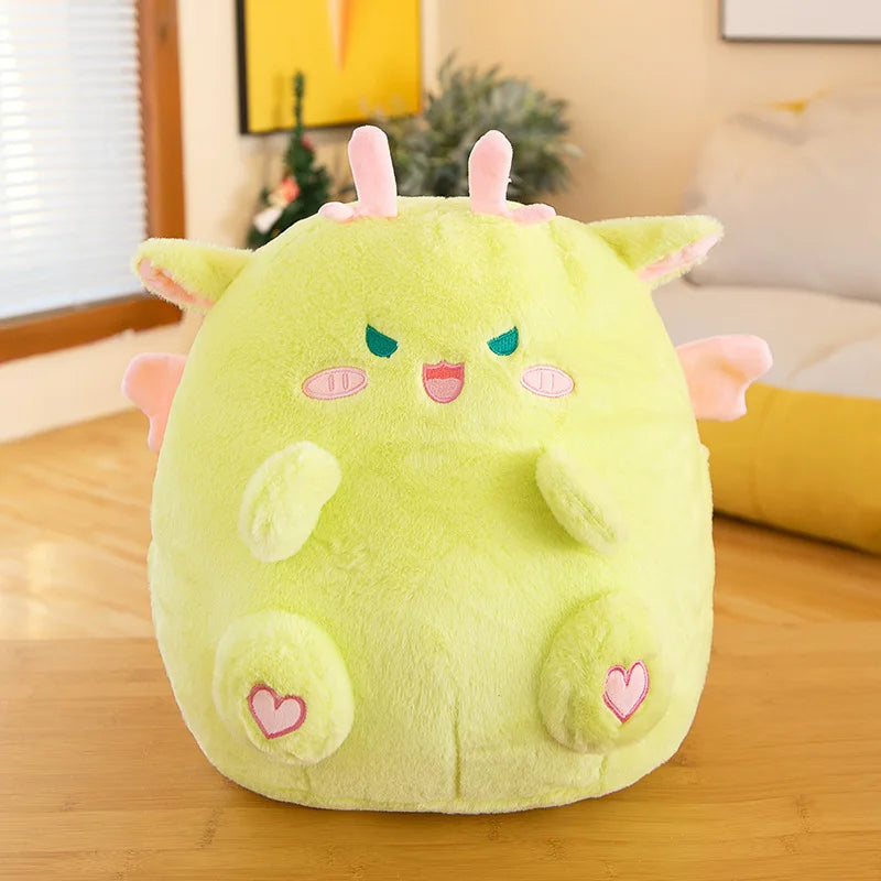 Green kawaii plush toy with pink accents on a wooden surface