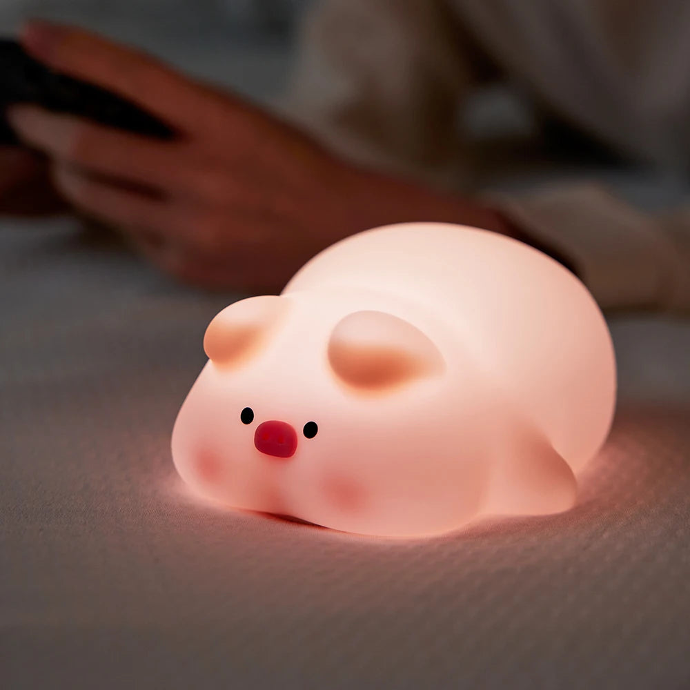 Pink kawaii pig-shaped night light on a soft surface with a blurred background