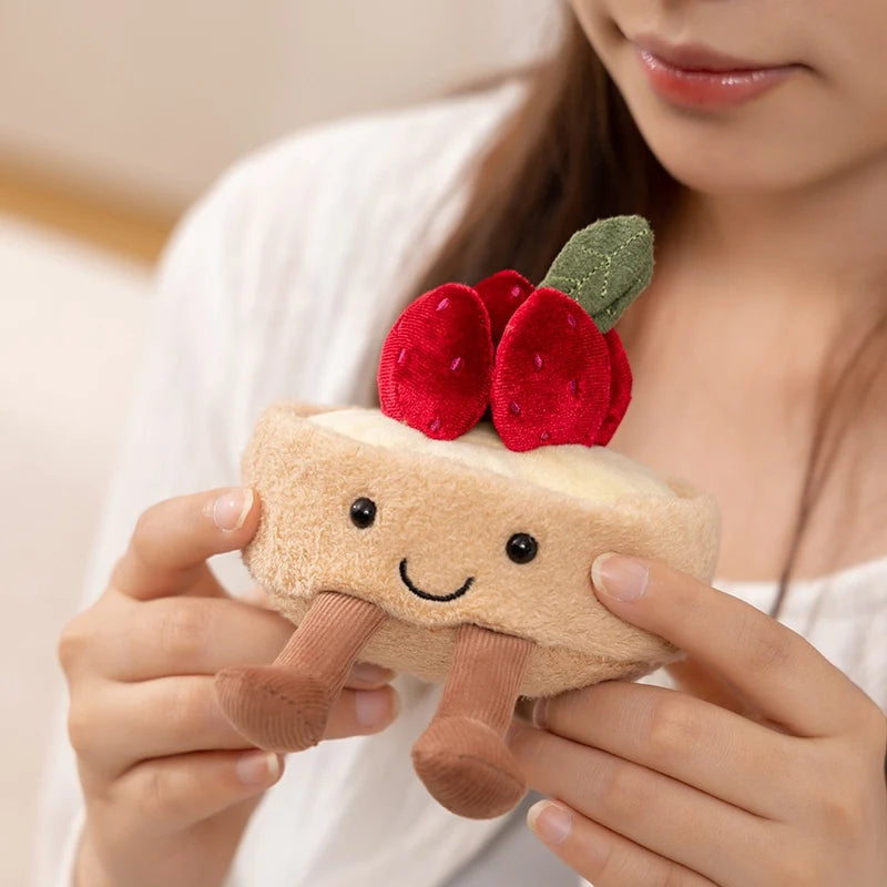 Person holding a plush kawaii toy resembling a slice of cake with cherry on top