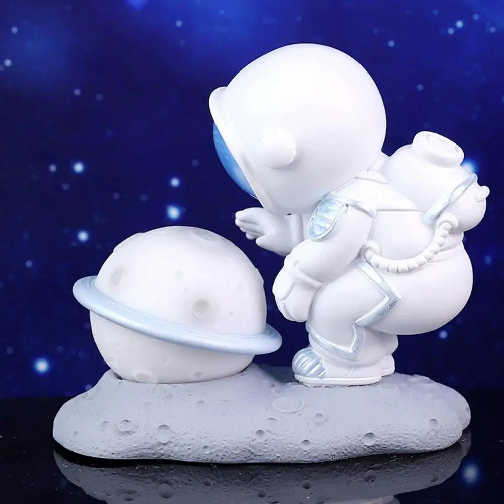 White ceramic figurine of an kawaii astronaut on a moon surface with a blue starry sky background