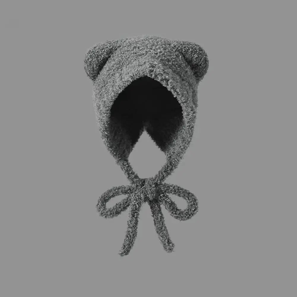 Textured knitted Kawaii bonnet with bow on a gray background