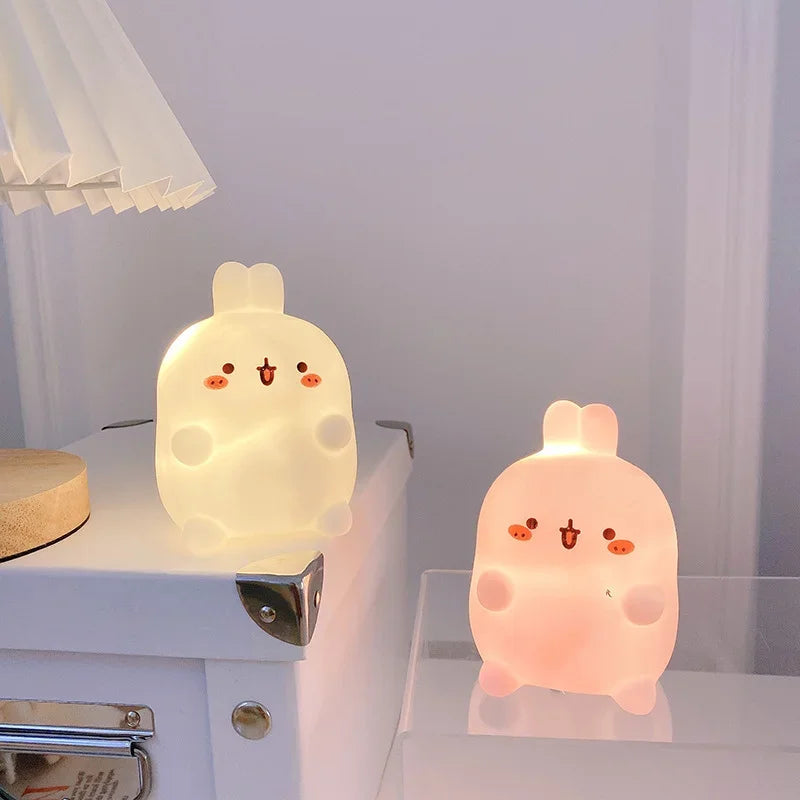 Two kawaii cartoon-style night lights on a surface with a neutral background