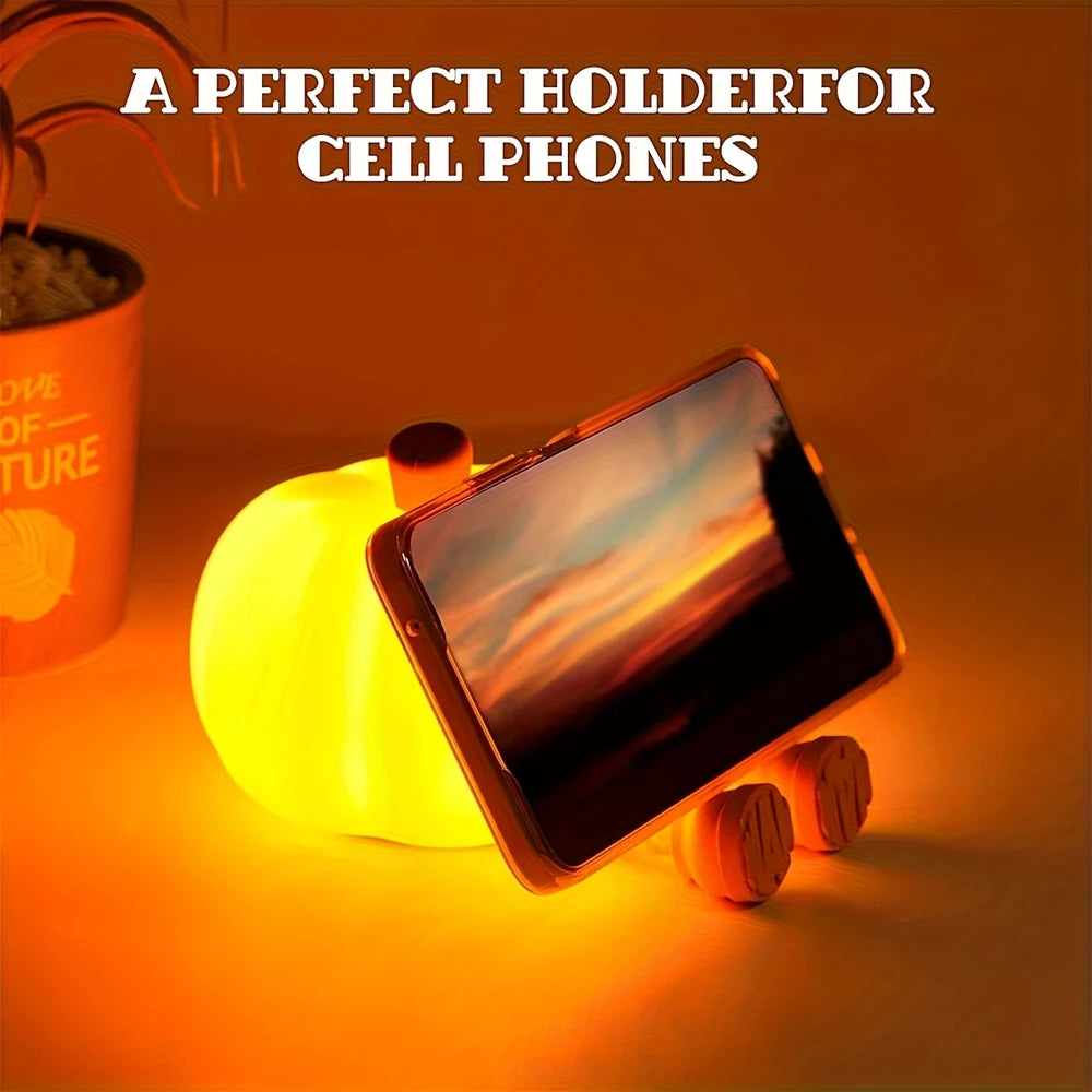 Kawaii pumpkin phone holder with glowing base on a warm-toned background