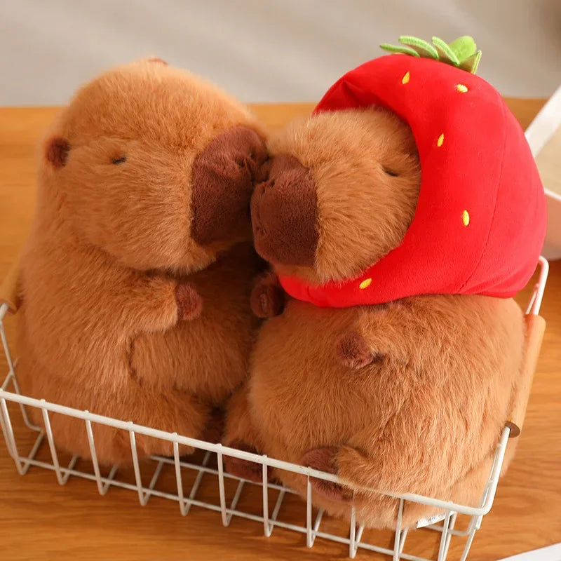 Two kawaii plush toys, one brown and one wearing a strawberry hat, in a white basket on a wooden surface.