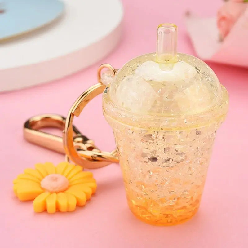Keychain shaped like a transparent kawaii cup with a straw and flower charm on a pink background