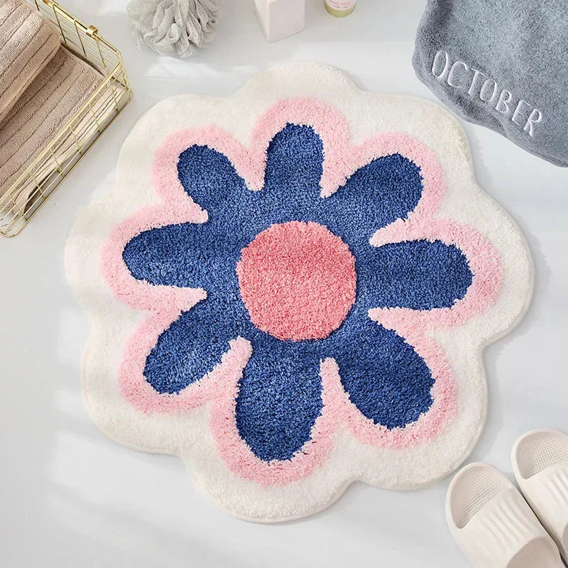 Floral-shaped kawaii bath mat with blue center and pink petals on a white surface.
