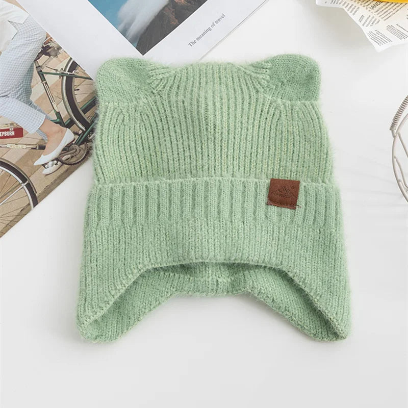 Green knitted Kawaii beanie with a brand label on a white surface