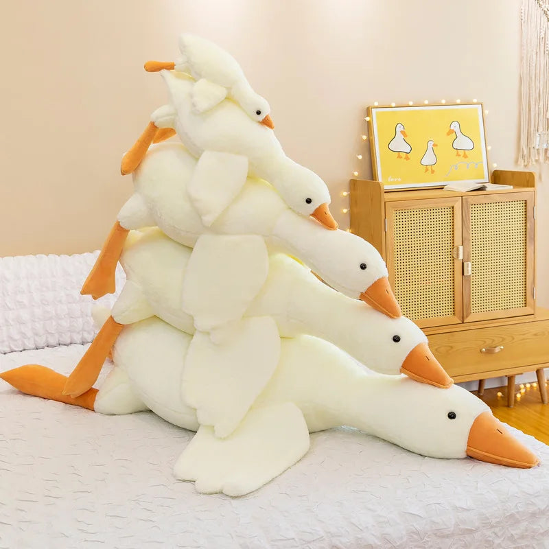 Stack of kawaii plush duck toys on a bed with a cabinet in the background