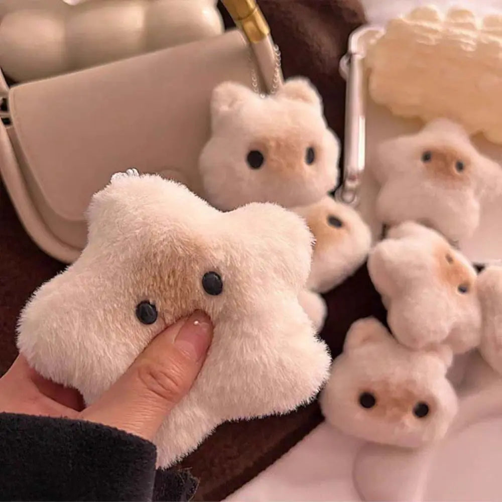 Fluffy white kawaii animal-shaped keychain held by a hand with more keychains in the background.