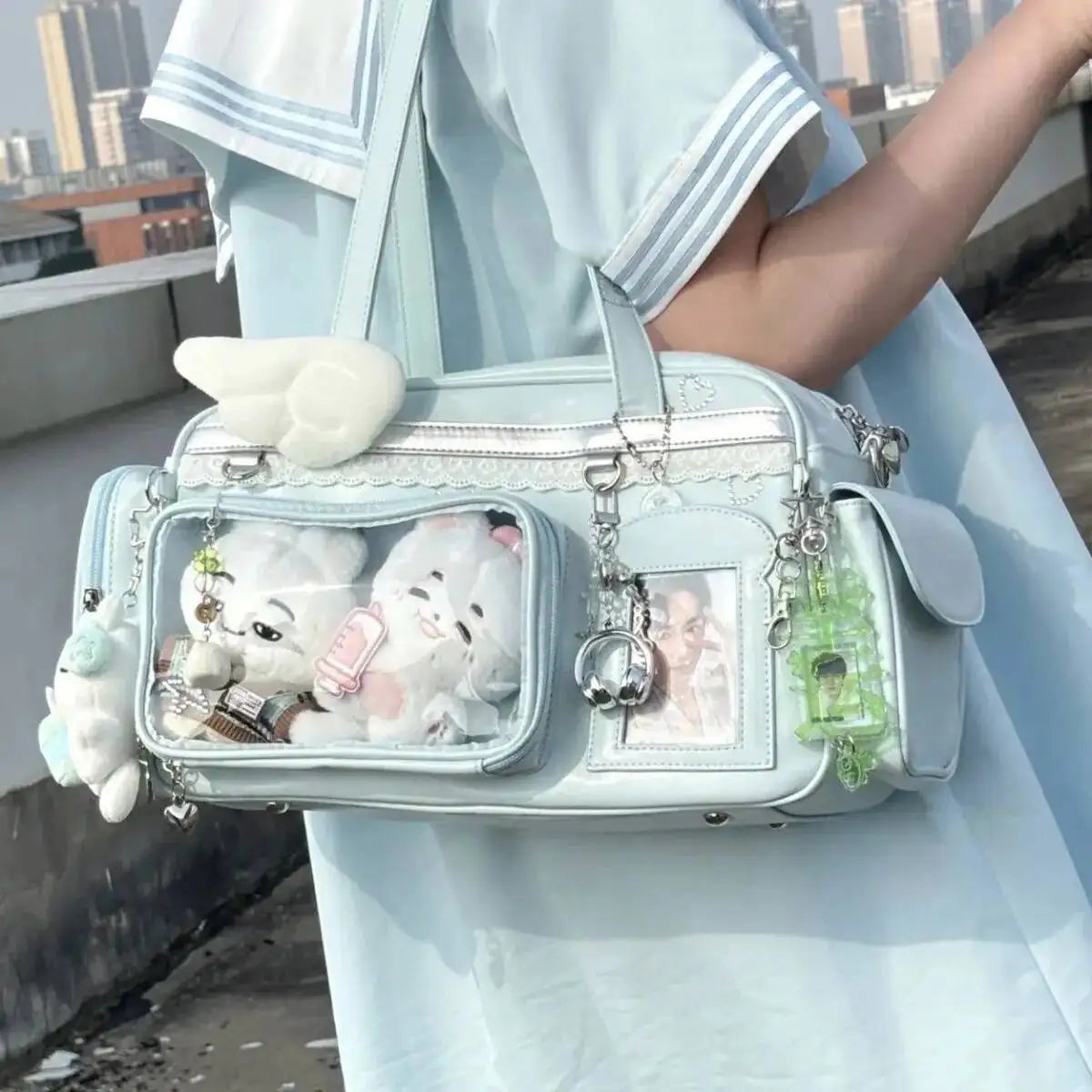 Light blue Kawaii handbag with decorative charms held by a person in a light blue outfit.