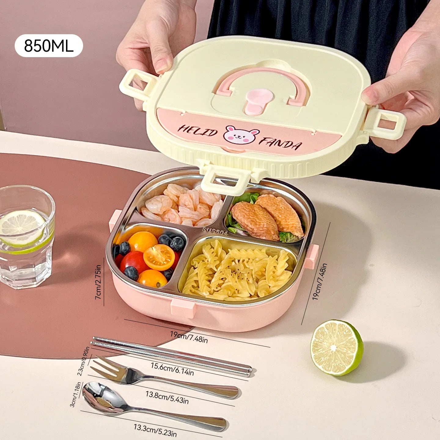 Pink and beige kawaii bento box with compartments filled with food, on a pink surface with utensils and a lime.