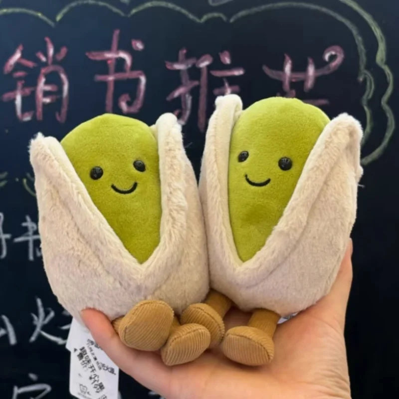 Two kawaii plush pistachios held in a hand with a blackboard background
