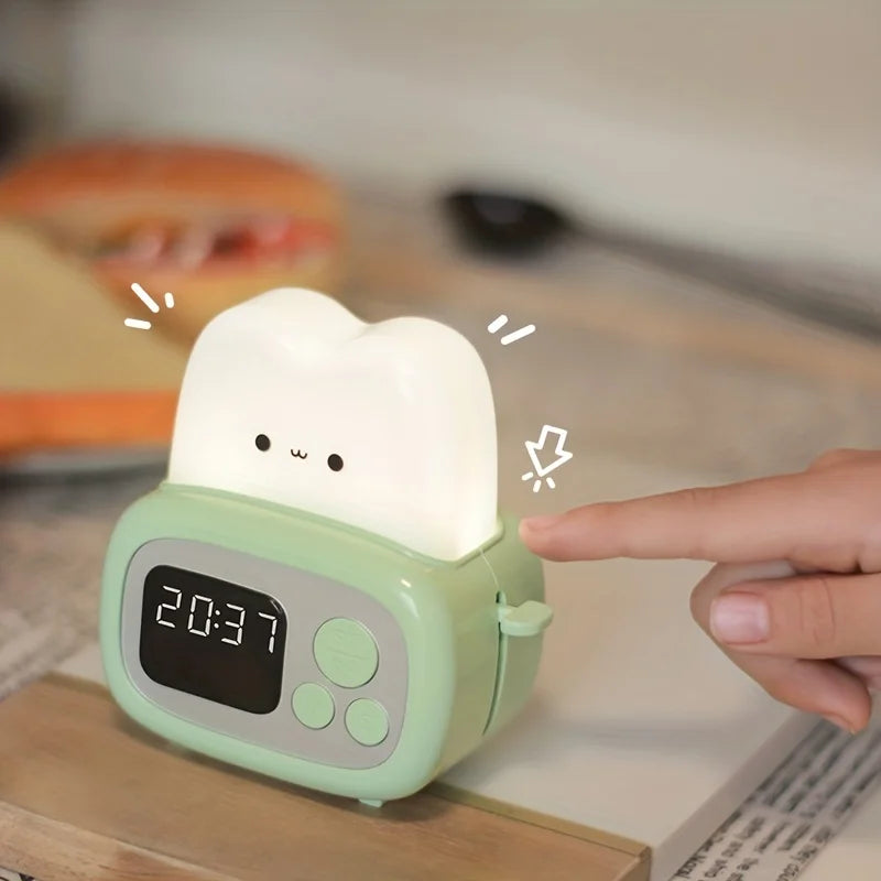 Green kawaii night light with digital display on a wooden surface, being touched by a hand.