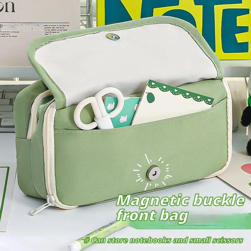 Green kawaii bag with magnetic buckle, notebooks, and scissors on a table.