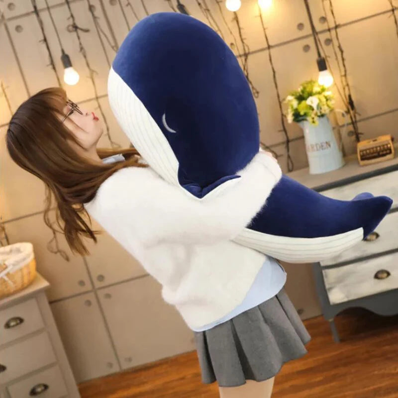Person holding a large blue and white plush shark kawaii toy in a room.