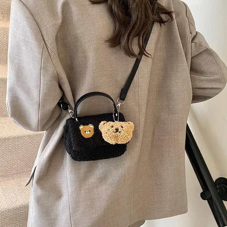 Person wearing a black handbag with Kawaii teddy bear faces on a neutral background