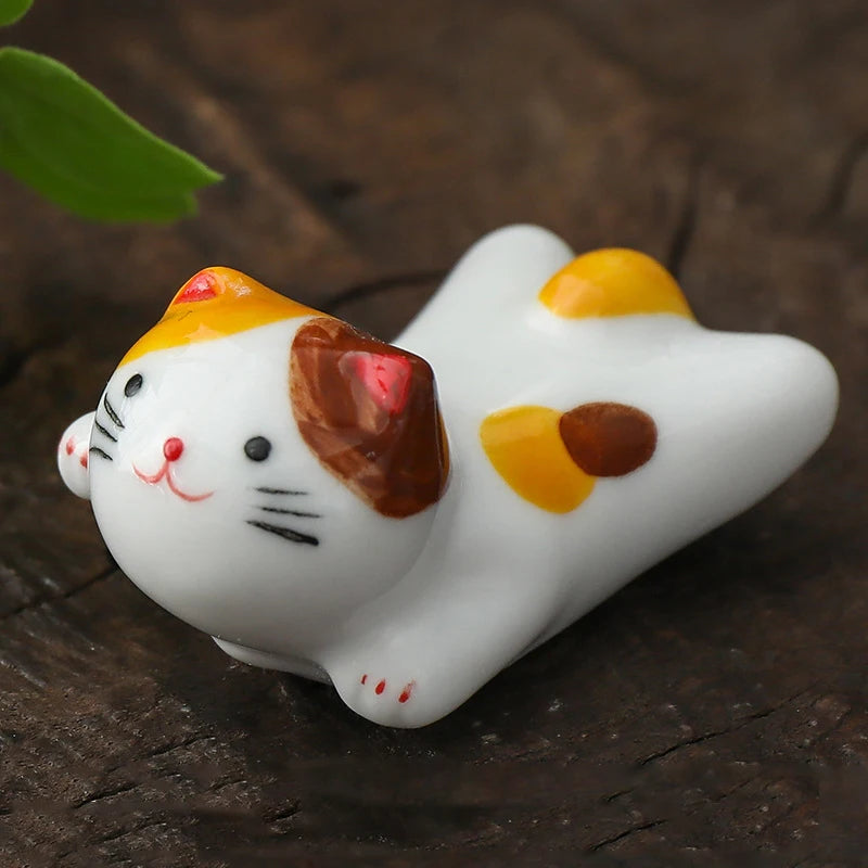White kawaii cat figurine with brown and yellow spots on a dark wooden surface
