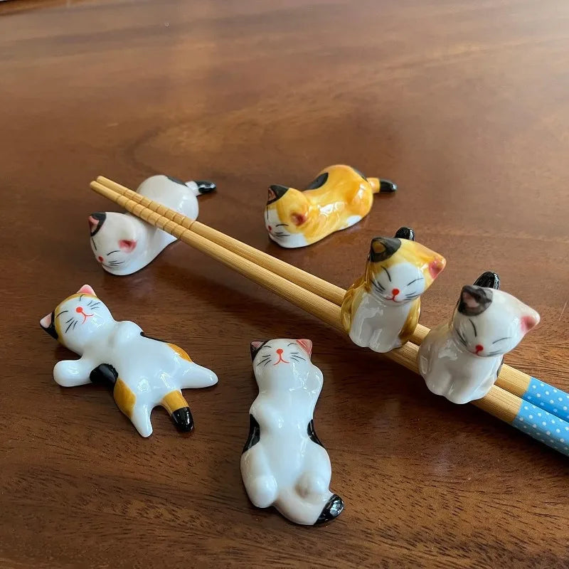 Set of kawaii cat-shaped ceramic chopstick rests on a wooden surface
