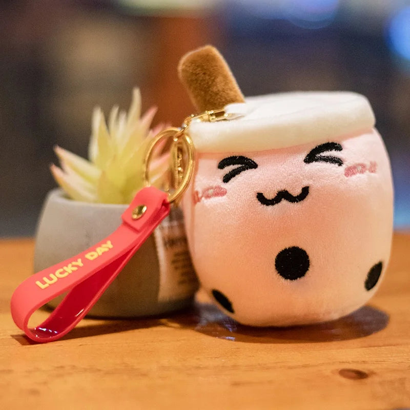 Plush toy resembling a kawaii cartoon cup with a keychain on a wooden surface