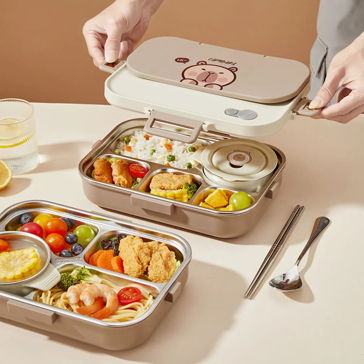 Kawaii bento box with compartments filled with food on a table with a glass of water and utensils.