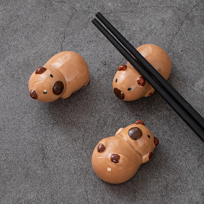 Three small kawaii animal-shaped objects on a gray surface with black chopsticks.