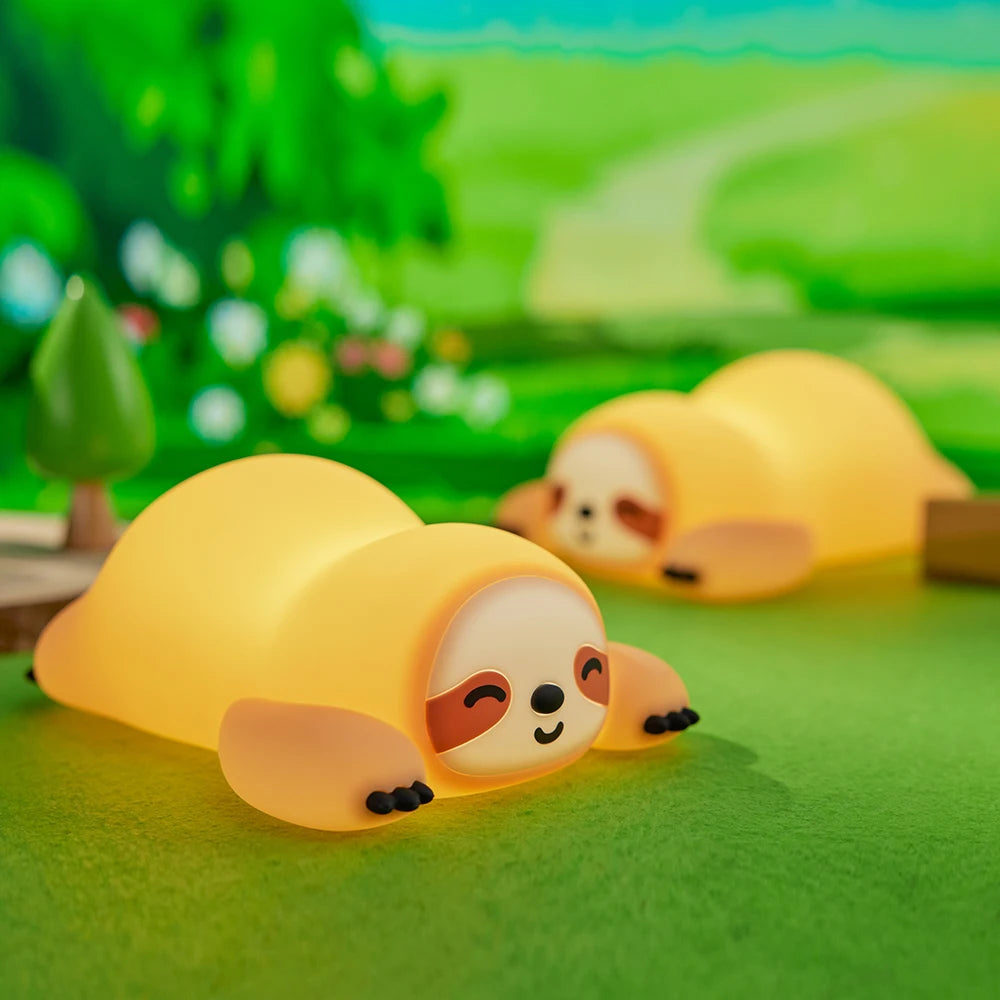 Two yellow sloth kawaii toys on a green surface with a blurred natural background