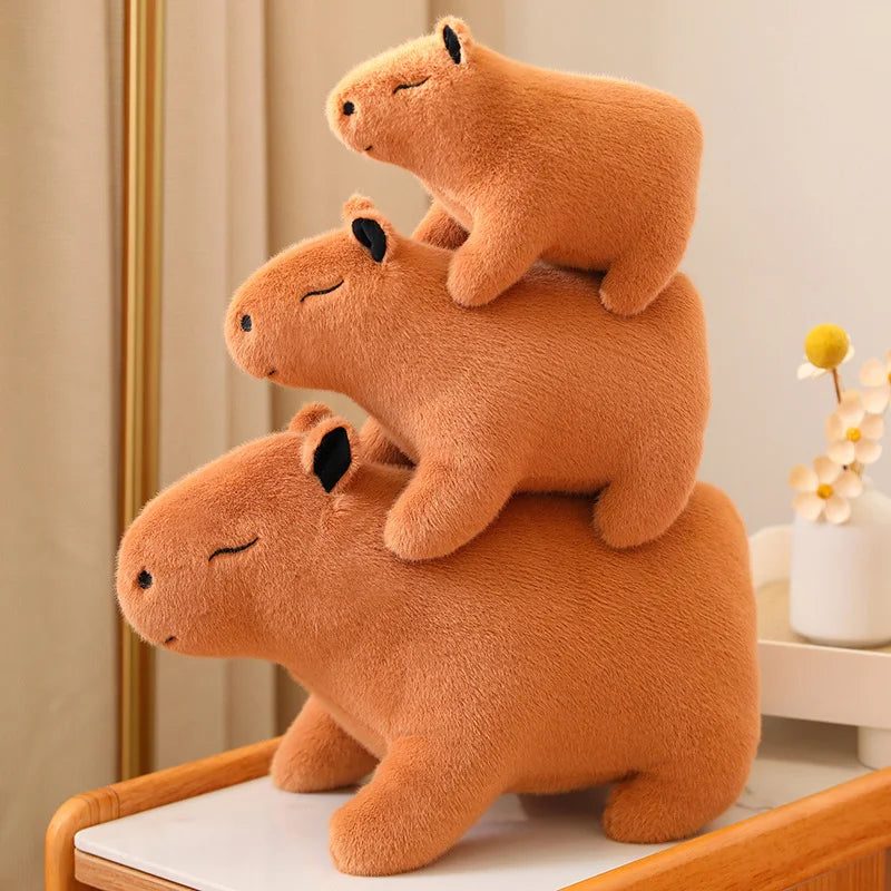 Stack of three brown kawaii plush capybaras on a chair