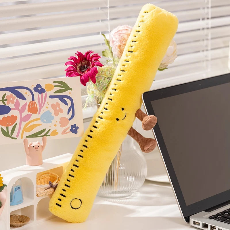 Yellow kawaii plush toy resembling a banana on a desk with a laptop and decorative items.