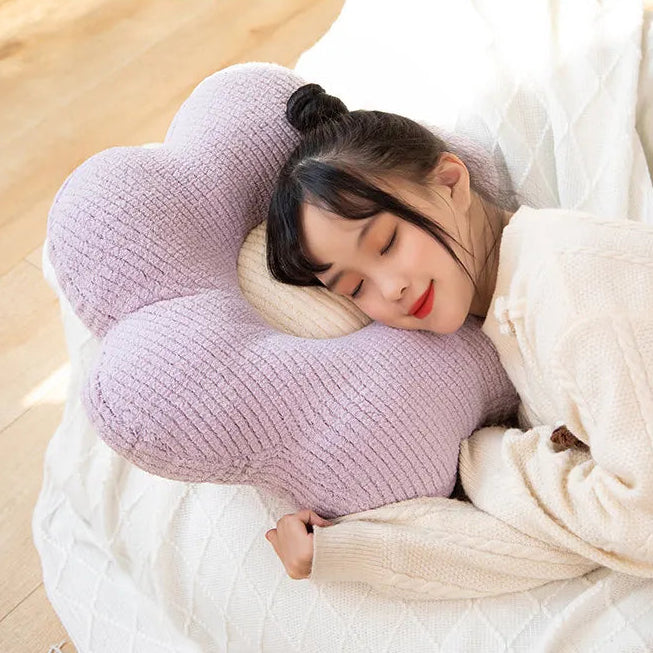 Woman sleeping with a purple U-shaped kawaii pillow on a wooden floor.