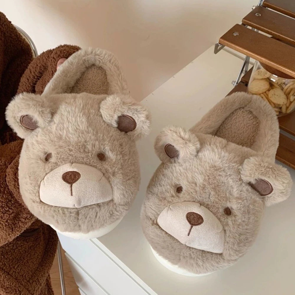Pair of bear-shaped kawaii slippers on a surface with a wooden chair in the background.