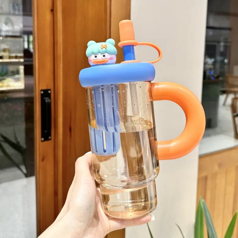 Clear water bottle with Kawaii orange handle and blue accents held by a hand indoors.