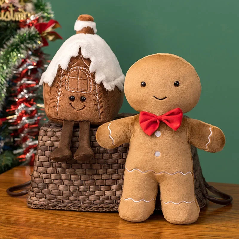 Gingerbread man kawaii plush toy with a small house on a wooden surface with a Christmas tree in the background.