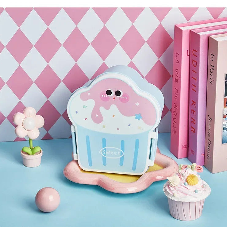 Cupcake-shaped kawaii toy with a pink and blue design on a checkered pink and white wall background.