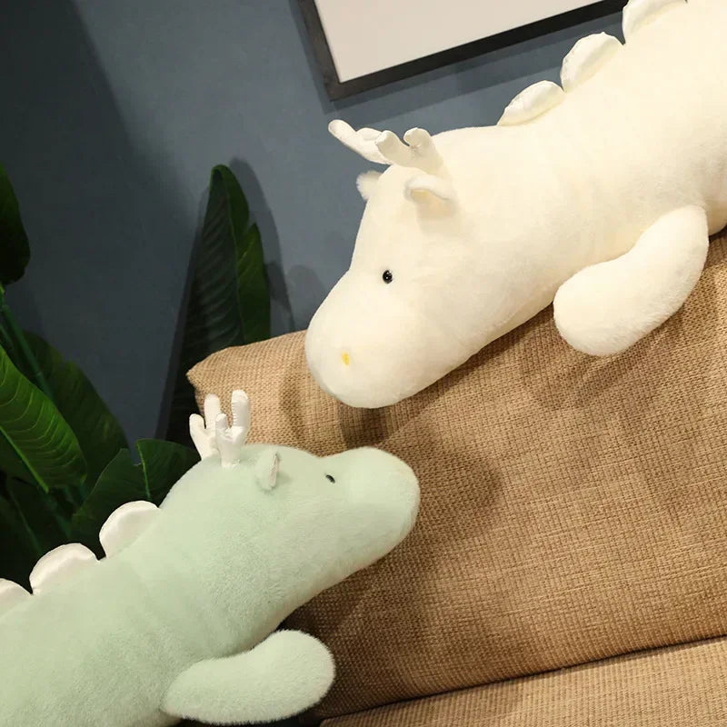 Two kawaii plush dragon toys on a brown couch with a plant in the background.
