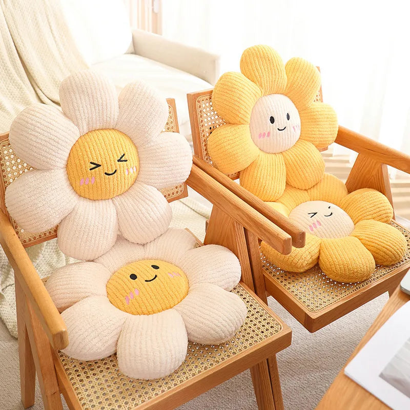 Two sunflower-shaped kawaii cushions with smiling faces on wooden chairs.
